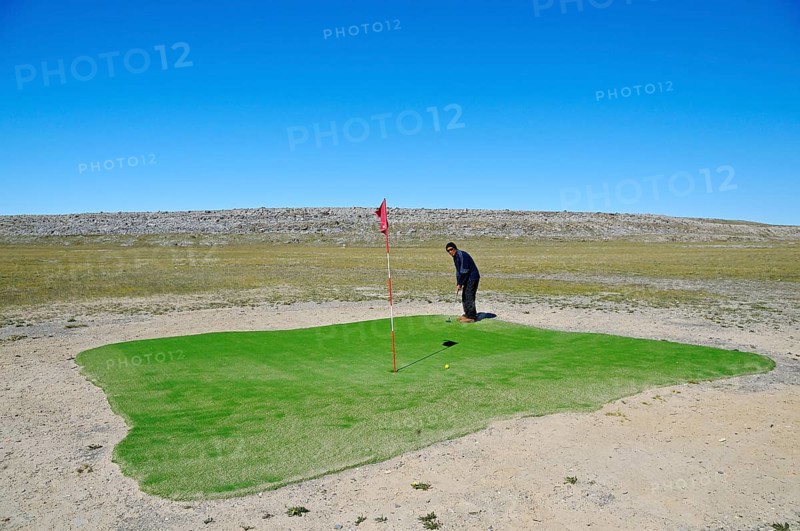Man hitting a golf ball on the northernmost golf course in the world