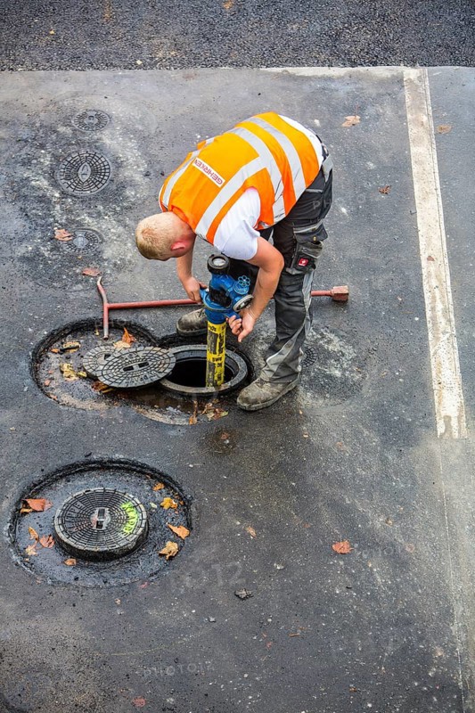 Road construction worker connecting a hydrant for water supply of the construction site