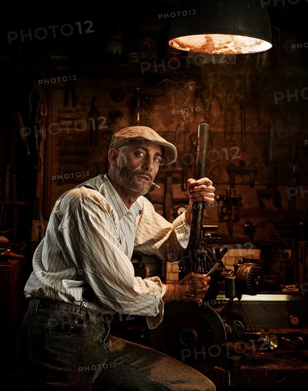 Man with hat and cigarette repairing a motor in a workshop
