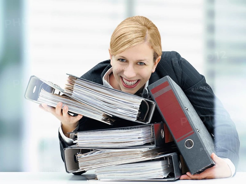 Smiling business woman holding a stack of folders