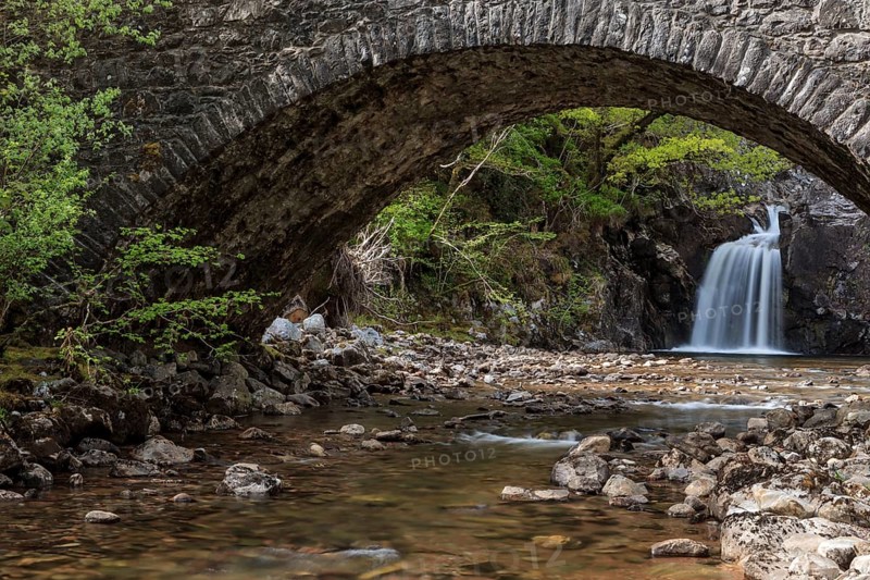 Waterfall behind an old stone bridge