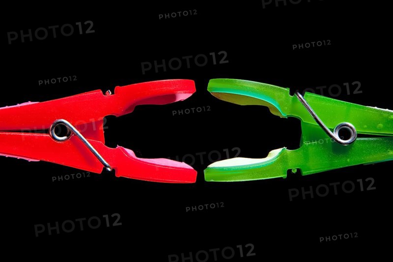 A red clothes-peg and a green clothes-peg are attacking each other