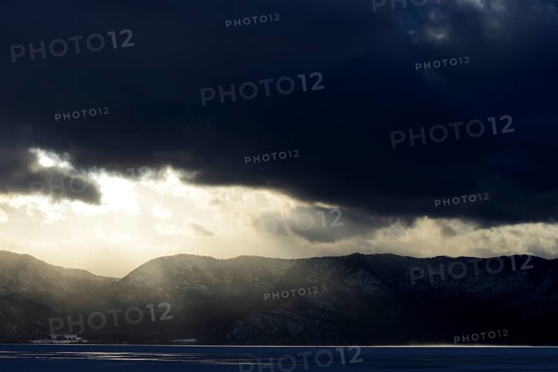 Sun breaks through the clouds at the frozen Lake Kussharo