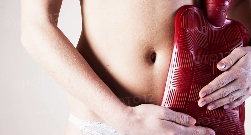 Young woman holding a hot water bottle on her stomach
