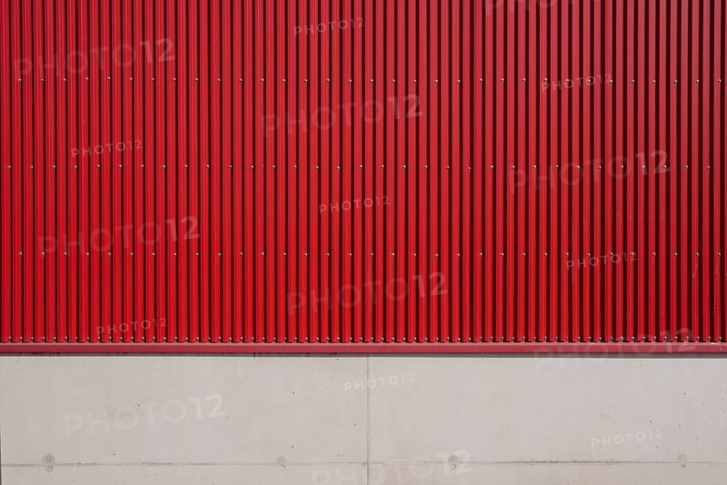Wall of a factory building with red corrugated iron and concrete