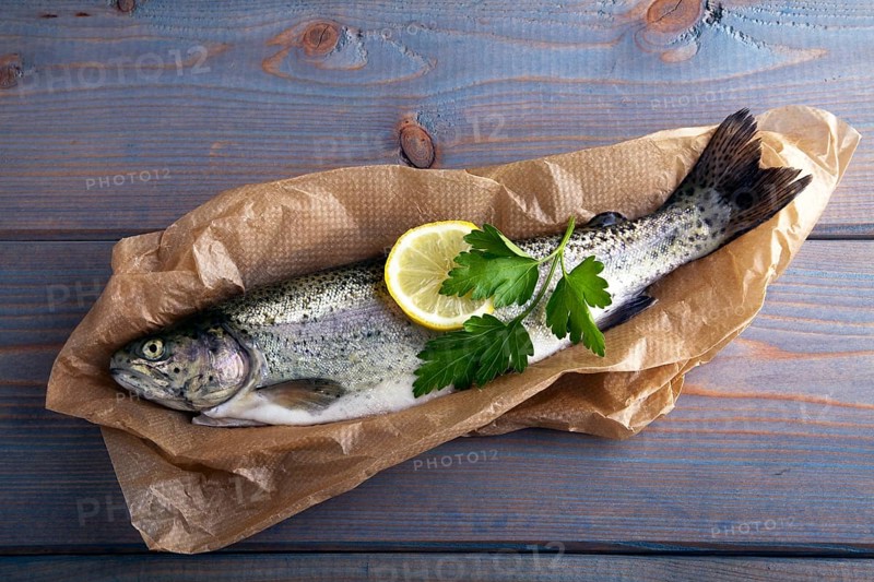 Fresh brook trout in baking paper on a wooden surface