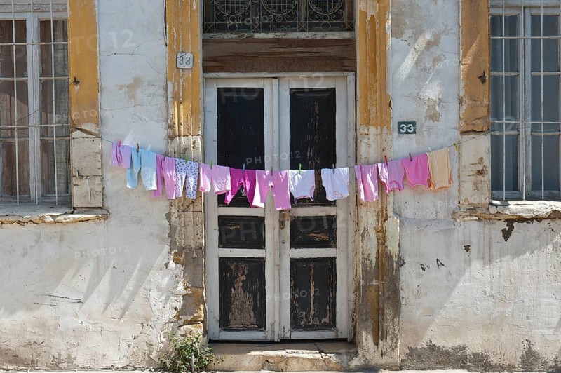 Clothesline with pink underwear hanging out to dry in front of an old door