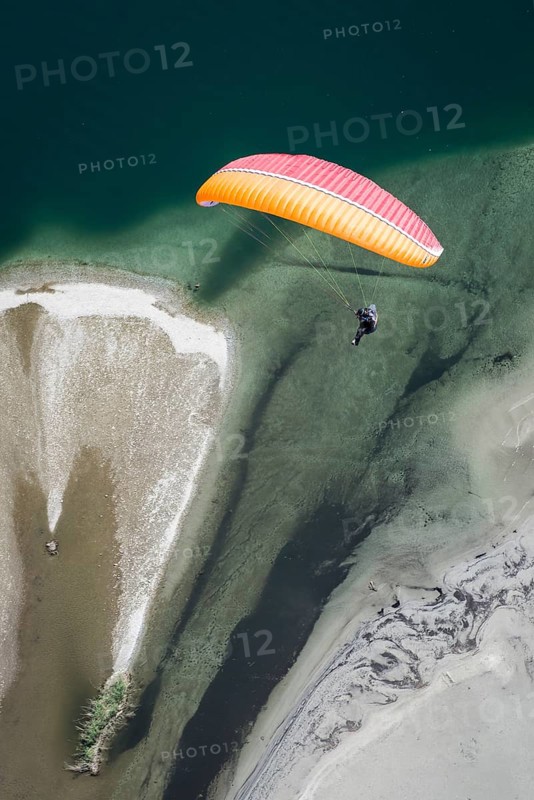 Paraglider over the Maggia river delta with naturally formed water and rocks terrain