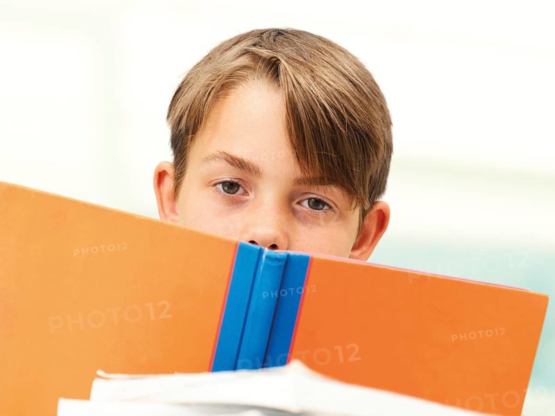Schoolboy behind a school book