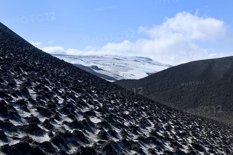 Ash-covered snowfield with the Eyjafjallajokull on the long-distance hiking trail from Skogar via Fimmvorouhals to the Thorsmork mountain ridge