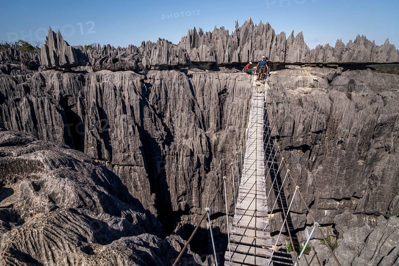 Tourist on suspension bridge over gorge in rugged limestone rocks