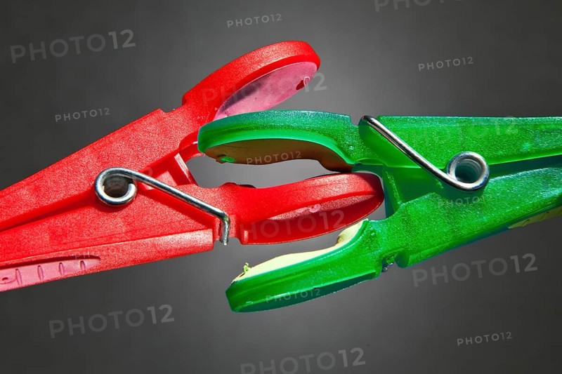 A red clothes-peg and a green clothes-peg are fighting with each other