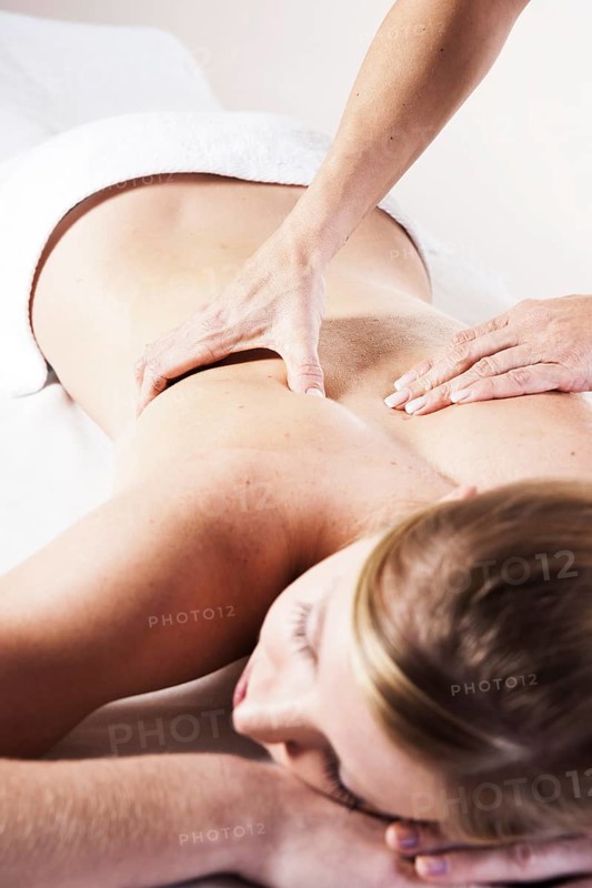 Young woman being massaged on the back by a therapist