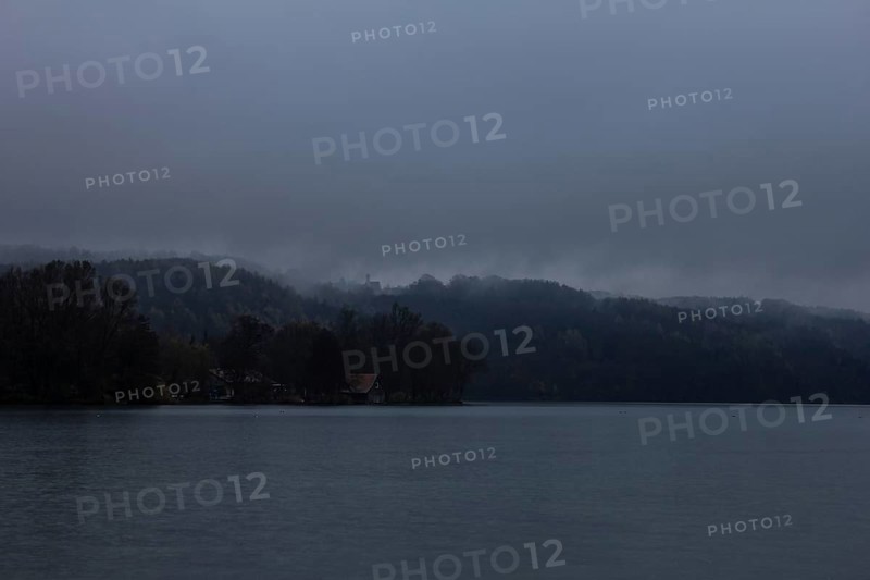 Autumn fog over the lake with a small church
