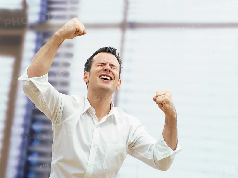 Businessman in an office cheering with clenched fists