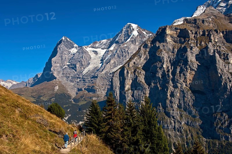 Hikers at the foot of Eiger and Moench Mountains and Eiger glacier