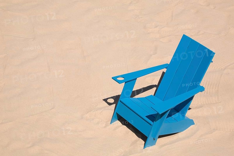 Blue adirondack chair standing on a beach