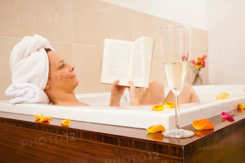 Woman taking a bath and reading a book