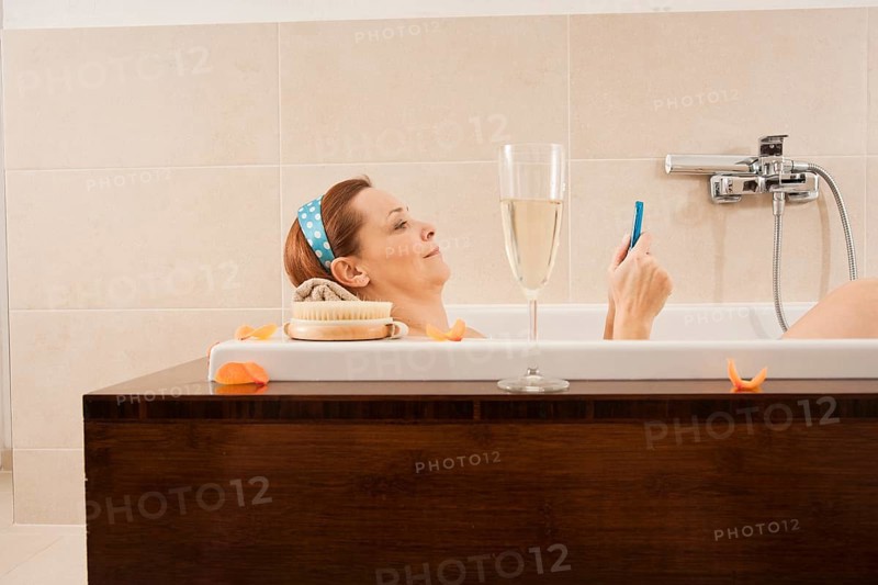 Woman using a mobile phone in the bathtub