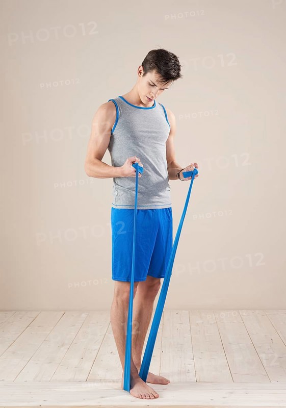 Young man doing fitness exercises with a resistance band