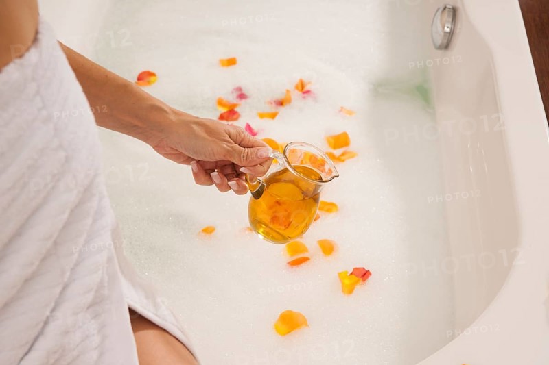 Woman pouring bath oil in a bathtub