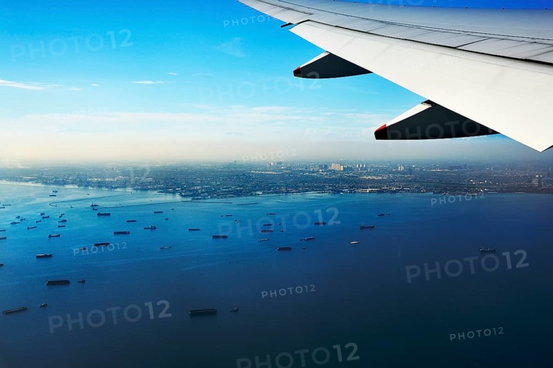 Wing of a plane and views of the port area of Jakarta on landing approach
