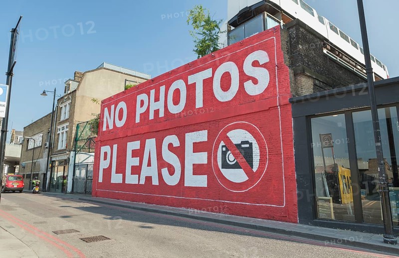 Graffiti 'No photos please' on a wall of the Village Underground building