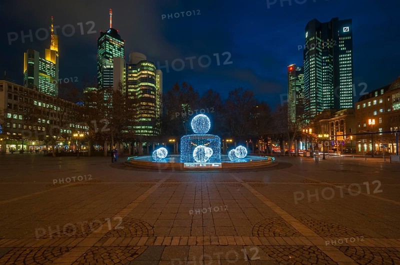 Illuminated Lucae Fountain on Opernplatz square in front of illuminated high-rise skyline