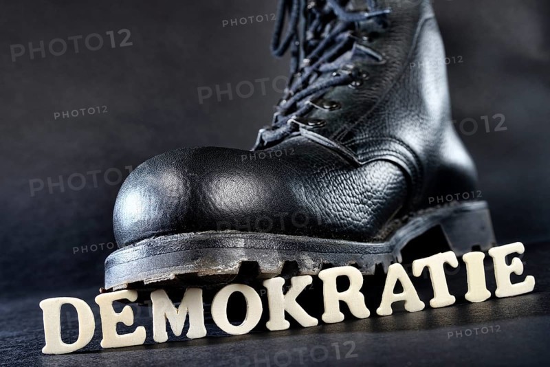 Combat boot standing on the word 'Demokratie'