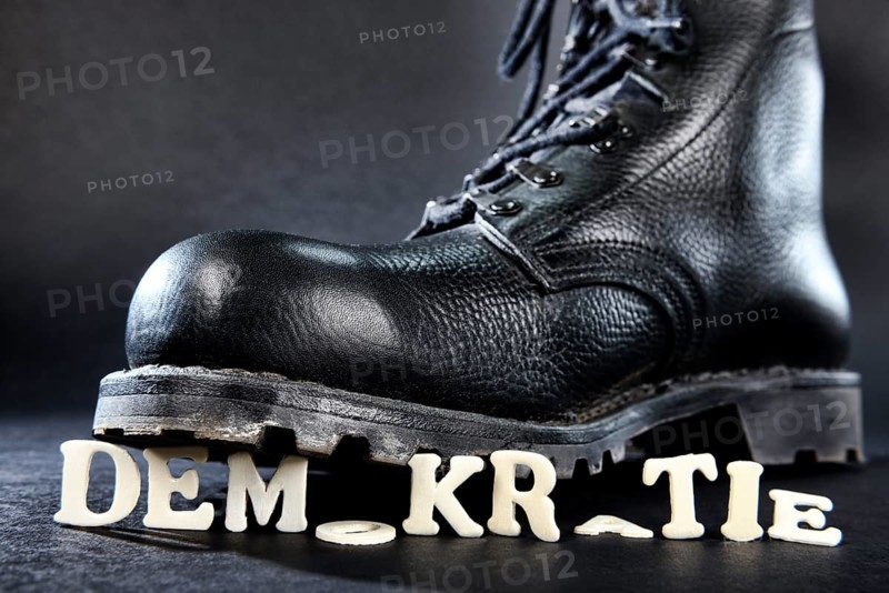 Combat boot standing on the word 'Demokratie'