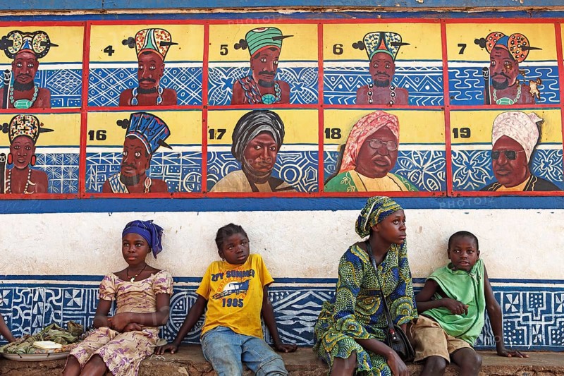 Boys and girls sitting in front of the row of ancestors on the Sultan's Palace of Foumban