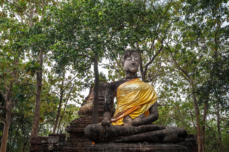 Seated Buddha statue in front of a chedi
