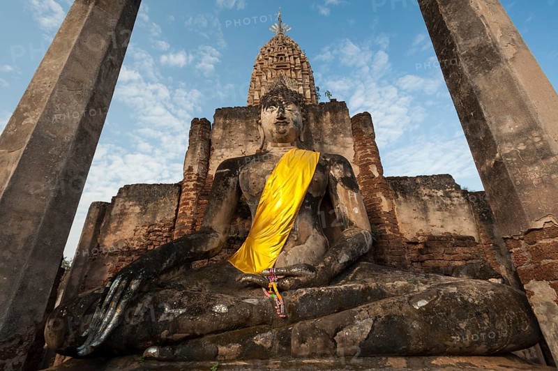 Seated Buddha statue in front of a chedi
