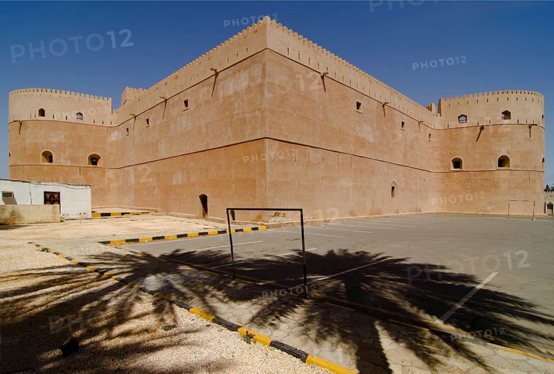 Al Hazm Castle behind the shadows of two palm trees
