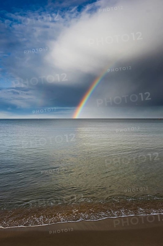 Sandy beach with rainbow over the sea