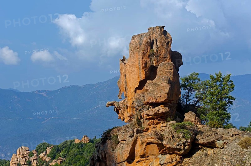 The typical bizarre red rocks of the Calanche of Piana below a blue sky and some clouds. The Calanche of Piana is in the western part of the island Corsica