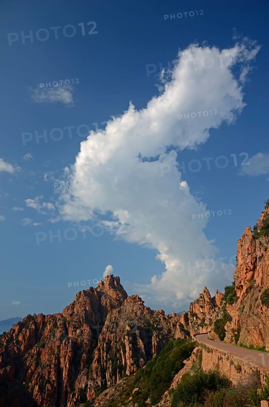 The typical bizarre red rocks of the Calanche of Piana below a blue sky and some clouds. The Calanche of Piana is in the western part of the island Corsica