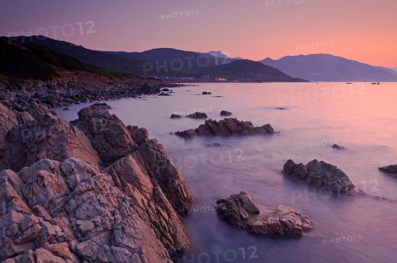 Sunrise behind the mountains of Corsica near Ajaccio with the rocky mediterranean coast on the foreground. Ajaccio is the capital of the mediterranean island of Corsica