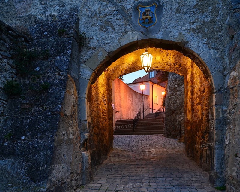 Lane passing underneath a stone archway at dusk