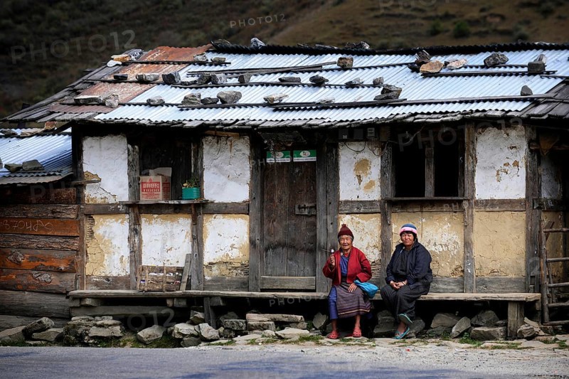 Two Bhutanese women sitting in front of a small shop on the roadside