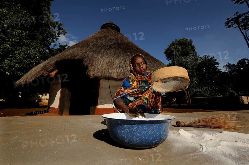 Young girl sifting flour in the village of Idool