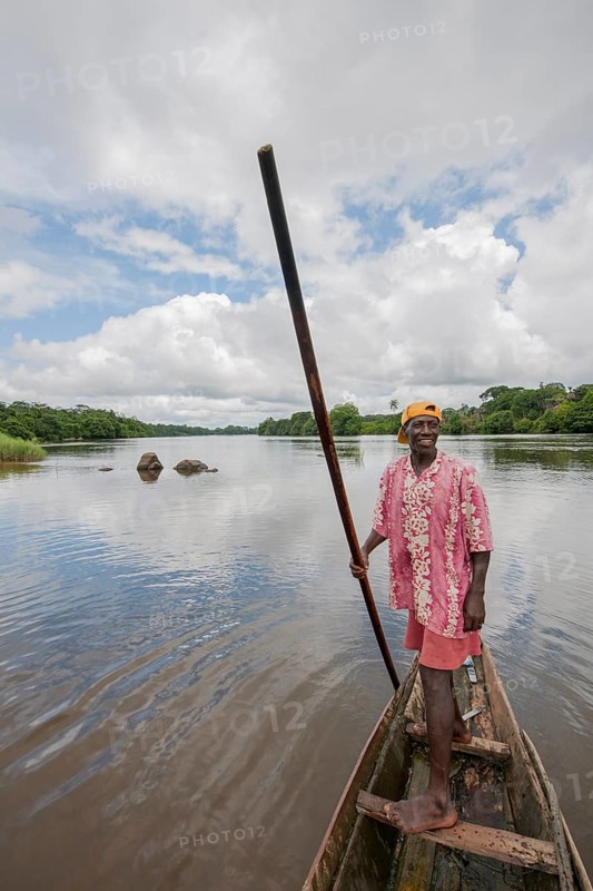 Man steering a pirogue on the Moa River at Tiwai Island Wildlife Sanctuary