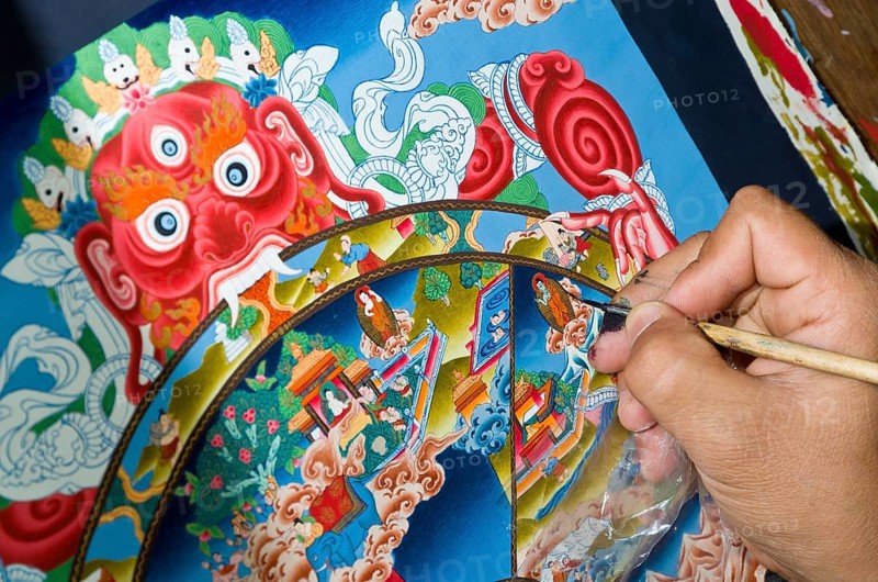 Artist painting a colourful Thangka in an art school