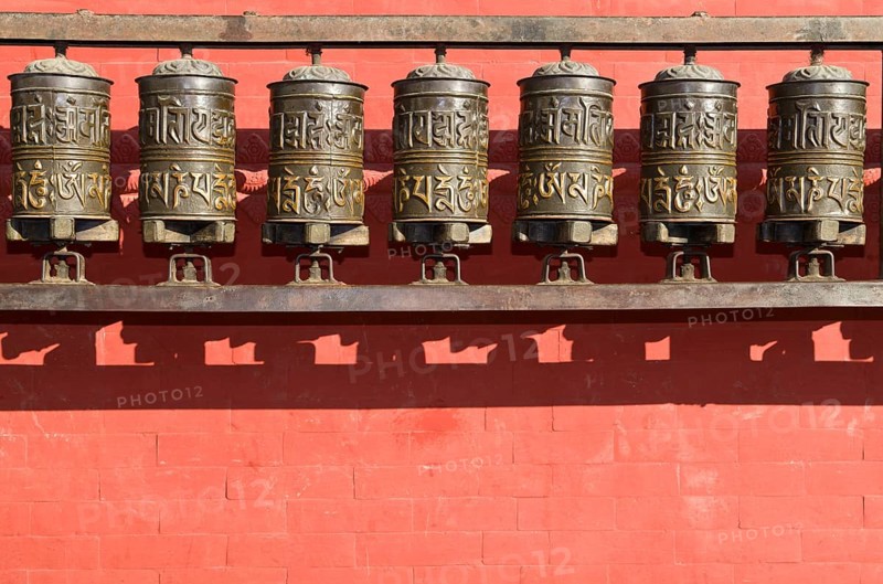 Buddhist prayer wheels in front of a red wall at Swayambhunath Stupa