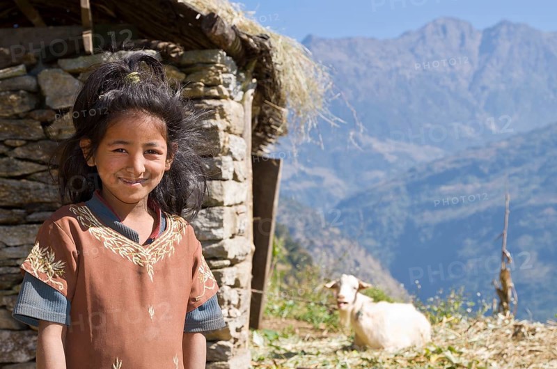 Portrait of a local girl with house and goat in the back
