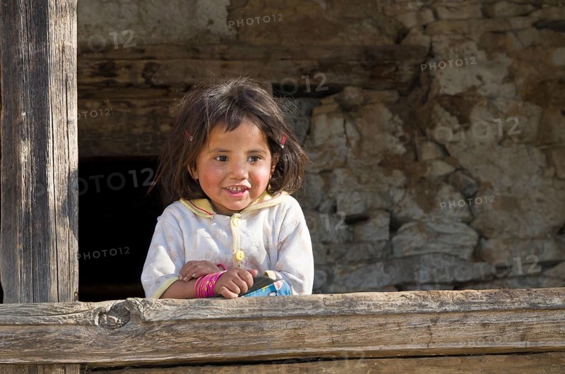Local little girl leaning on a wooden pole