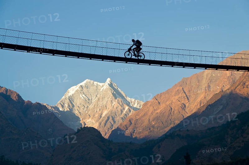 Cyclist crossing a suspension Bridge over Kali Ghandaki Valley