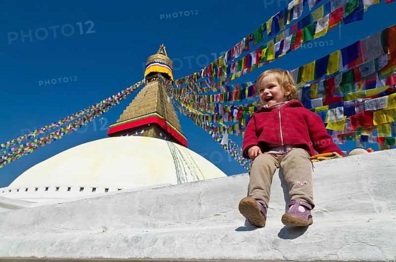 Little tourist child sitting at the foot of Boudnath Stupa