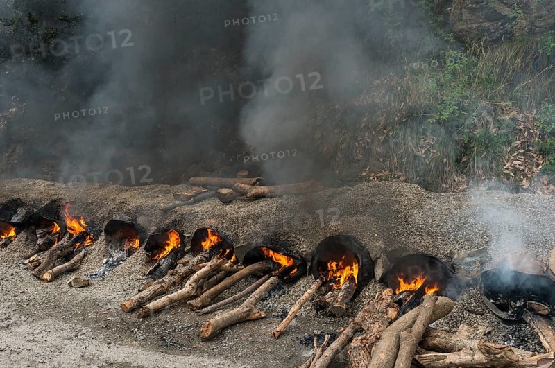 Gravel and hot tar being mixed on open fires at a road construction site