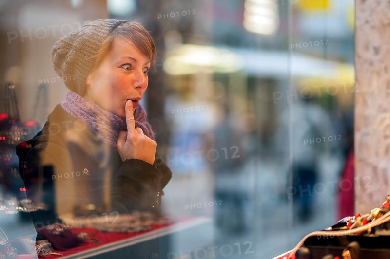 Young woman looking in the window of a jewellery store
